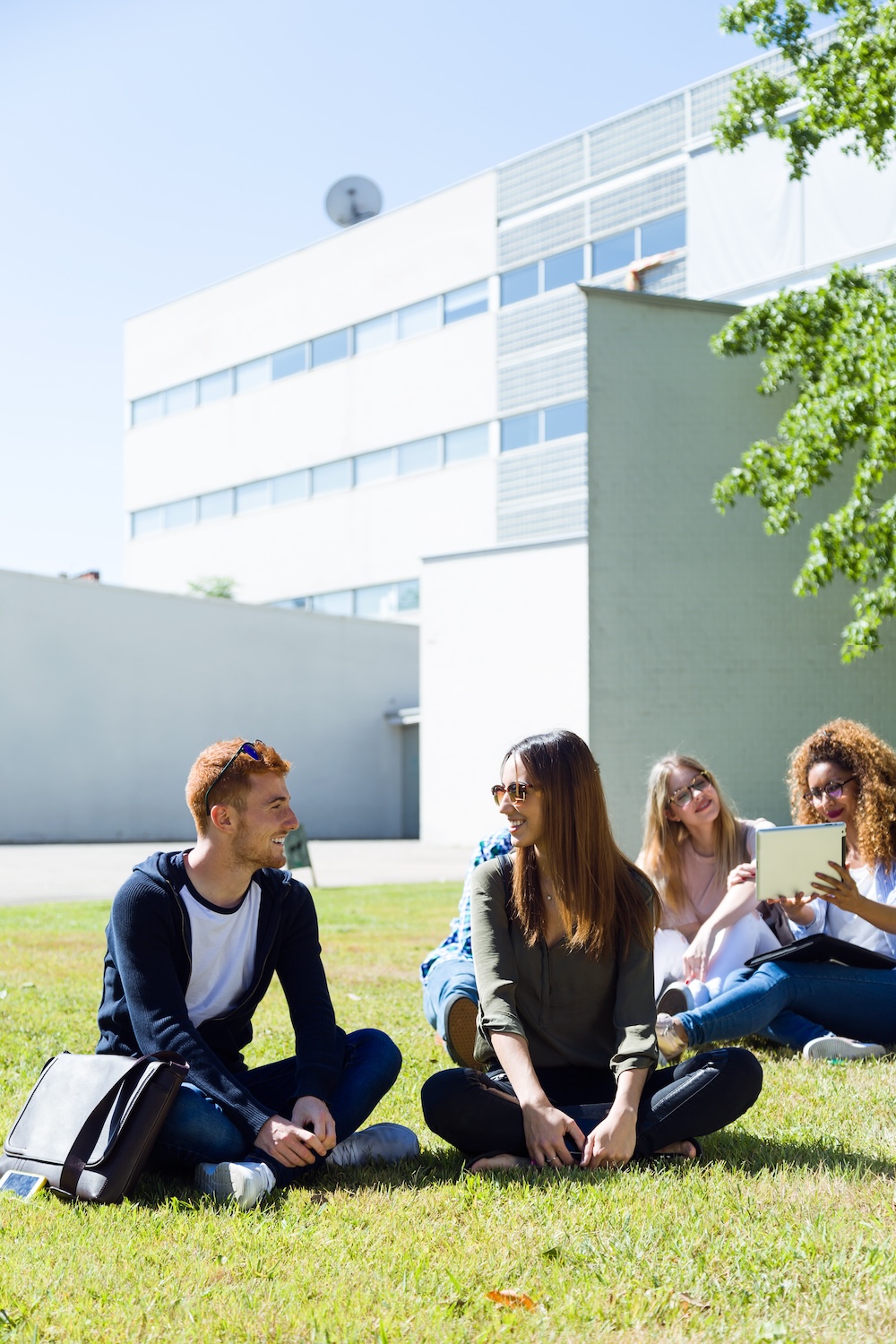 Portrait of happy students sitting outside on campus at the university.